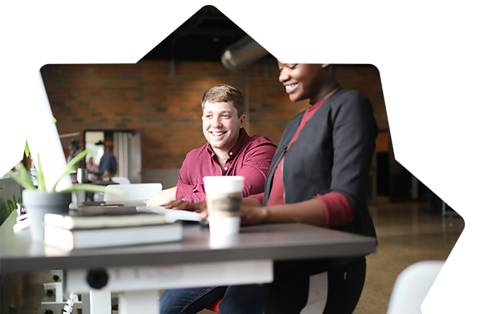 Two smiling colleagues collaborating at a PC