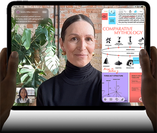 iPad Pro, front exterior, landscape orientation, space black colour, rounded corners, black display bezel, hands holding left and right sides, display showing a FaceTime conversation being live translated, and an educational app showing a presentation of Comparative Mythology with text, diagrams and handwritten notes