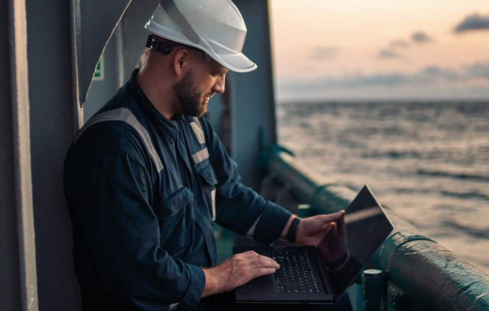 Man standing with a laptop on deck Man standing with a laptop