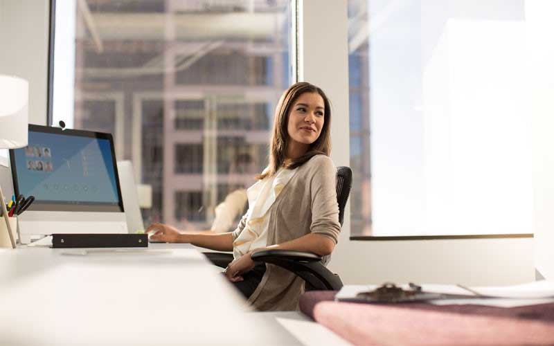 Software solutions from Cisco Young woman at desk with laptop reclining in her chair.