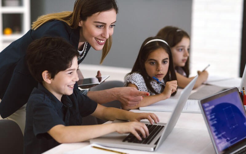 Empower your students and teachers with Intel-powered laptops and tablets Teacher with students on notebook computers